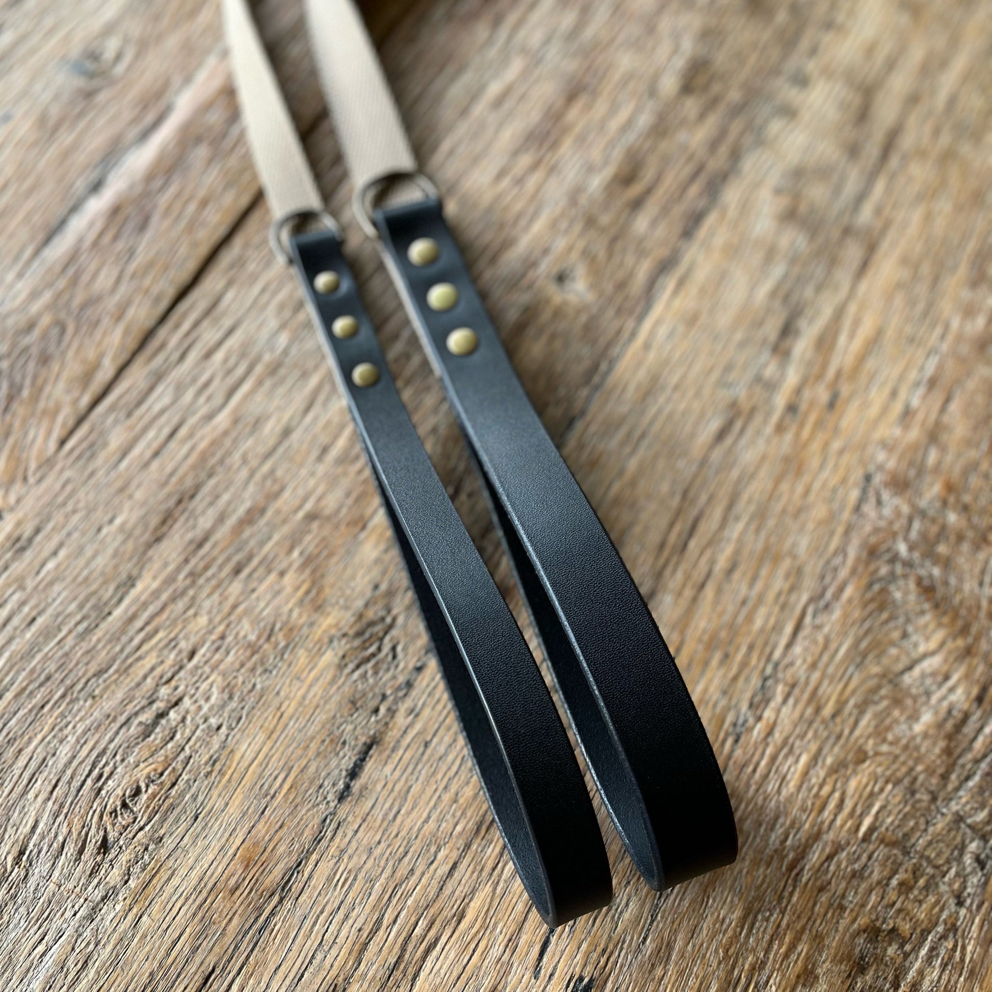 Black leather straps with gold rivets on a wooden surface