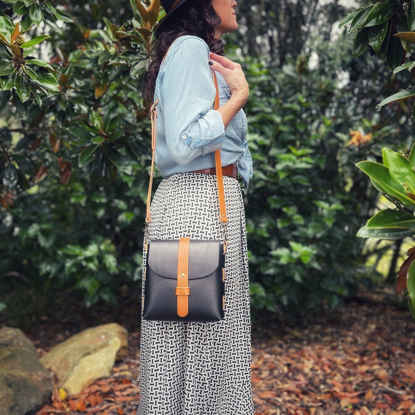 Model wears a black and tan small leather crossbody bag