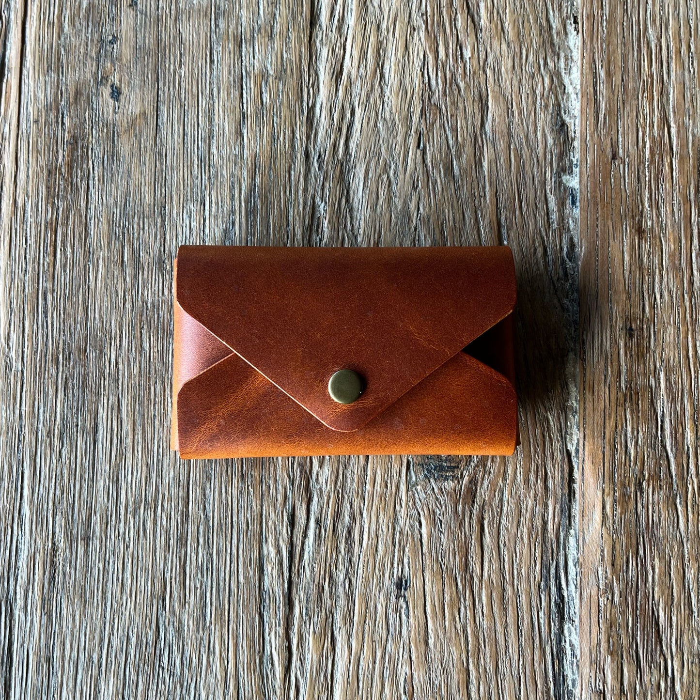 Brown leather wallet with a button on a wooden surface