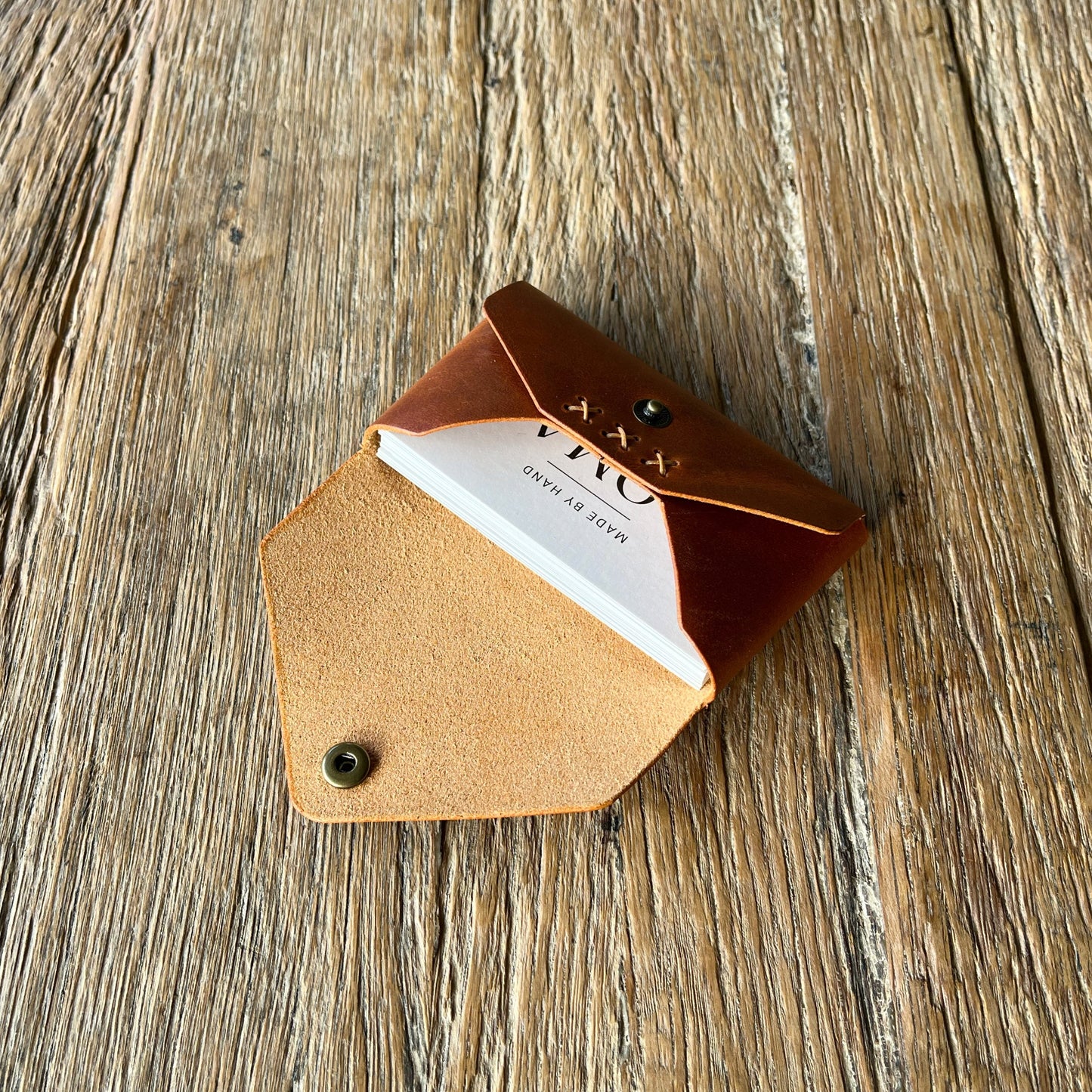 Brown leather cardholder holding business cards on a wooden surface