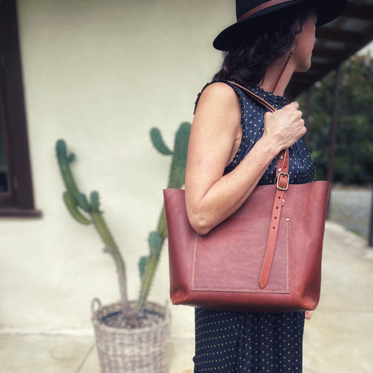 Model holds a Mackenzie leather tote bag in cognac