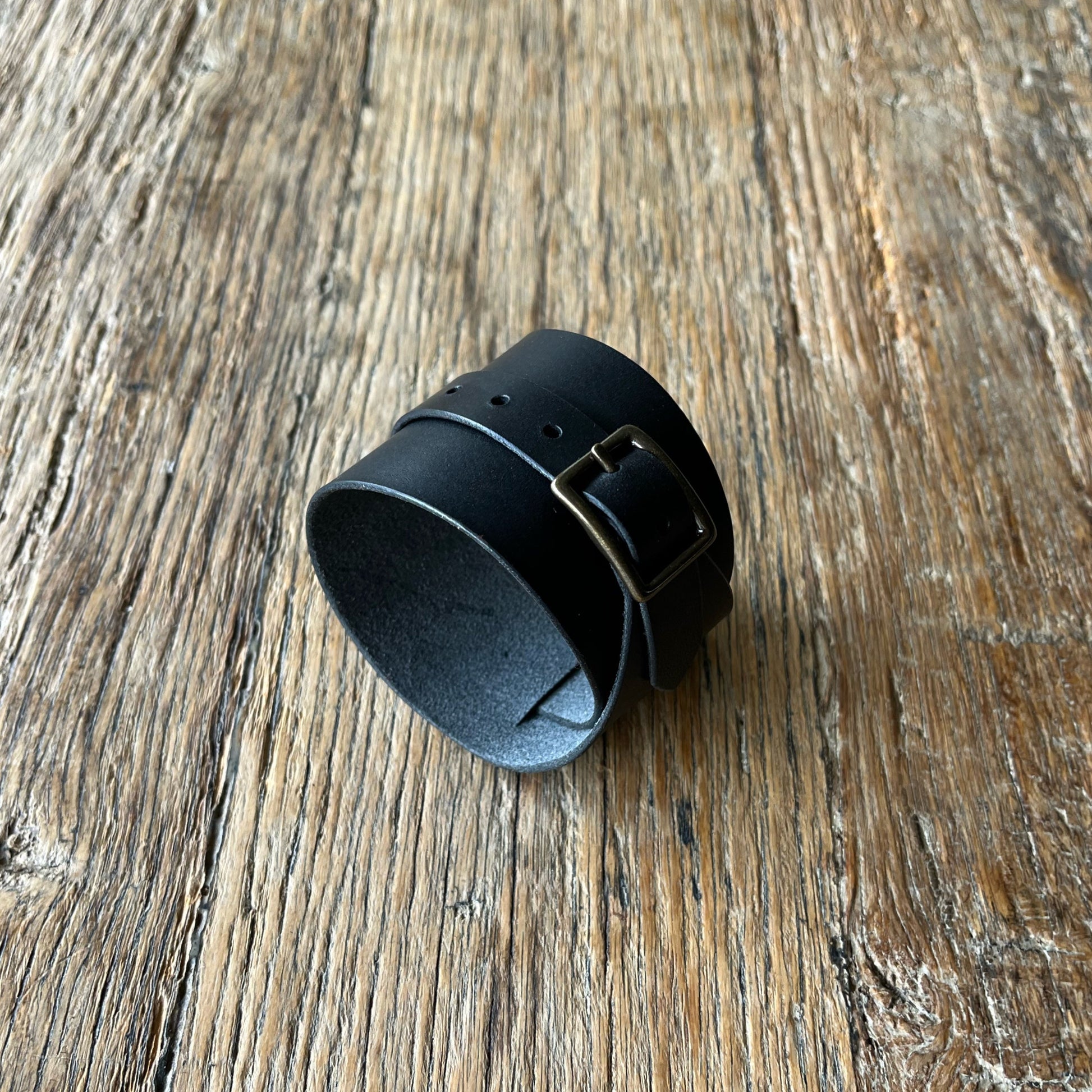Black leather cuff on a wooden surface