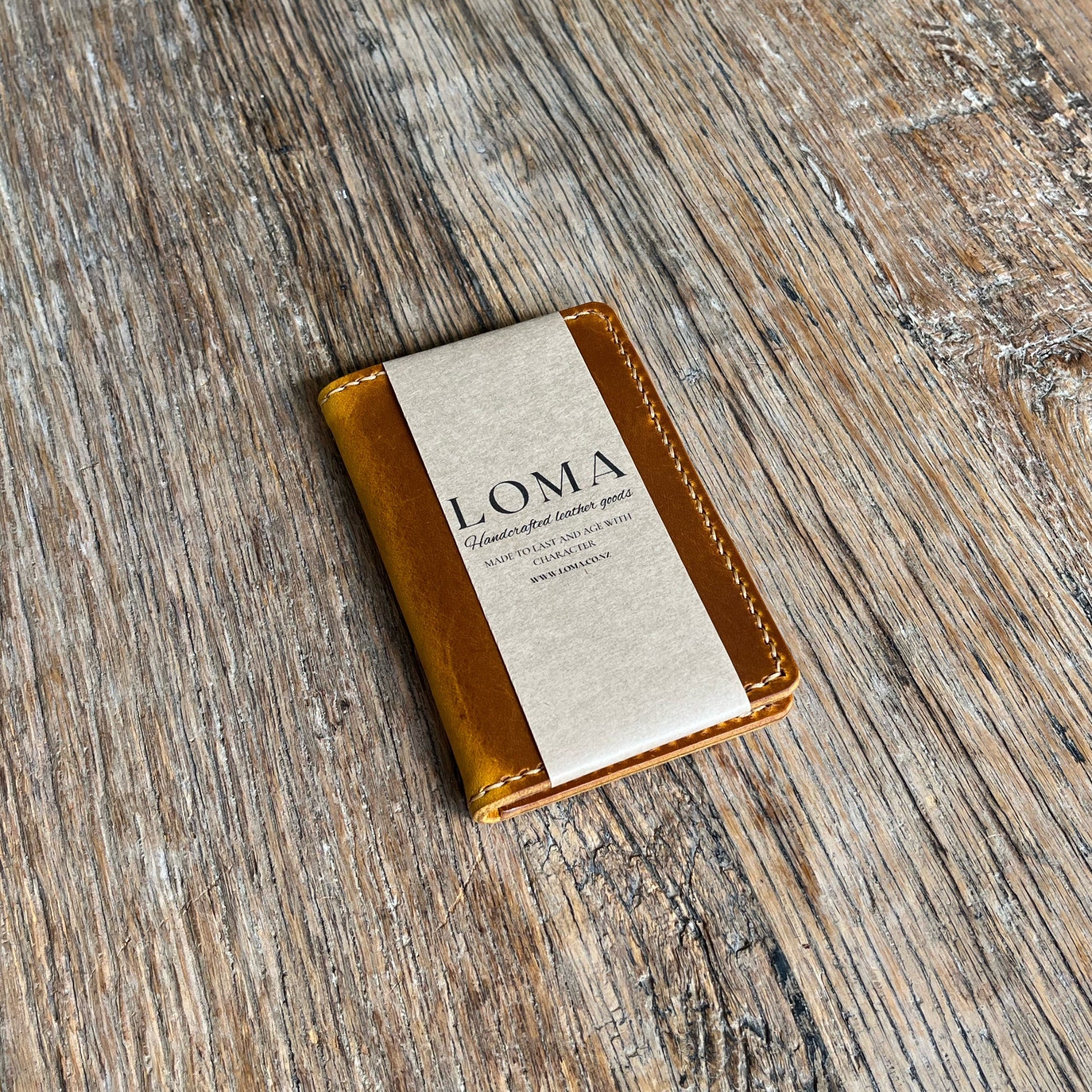 Leather goods with 'LOMA' branding on a wooden surface