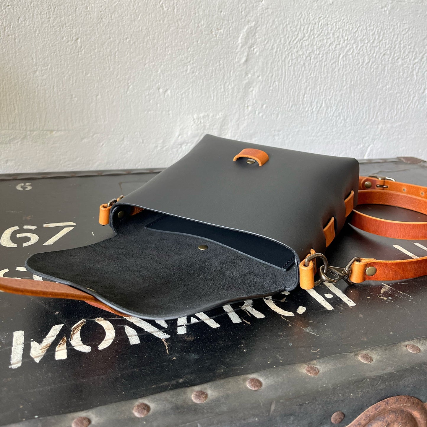 Black leather bag with tan accents on a metal surface