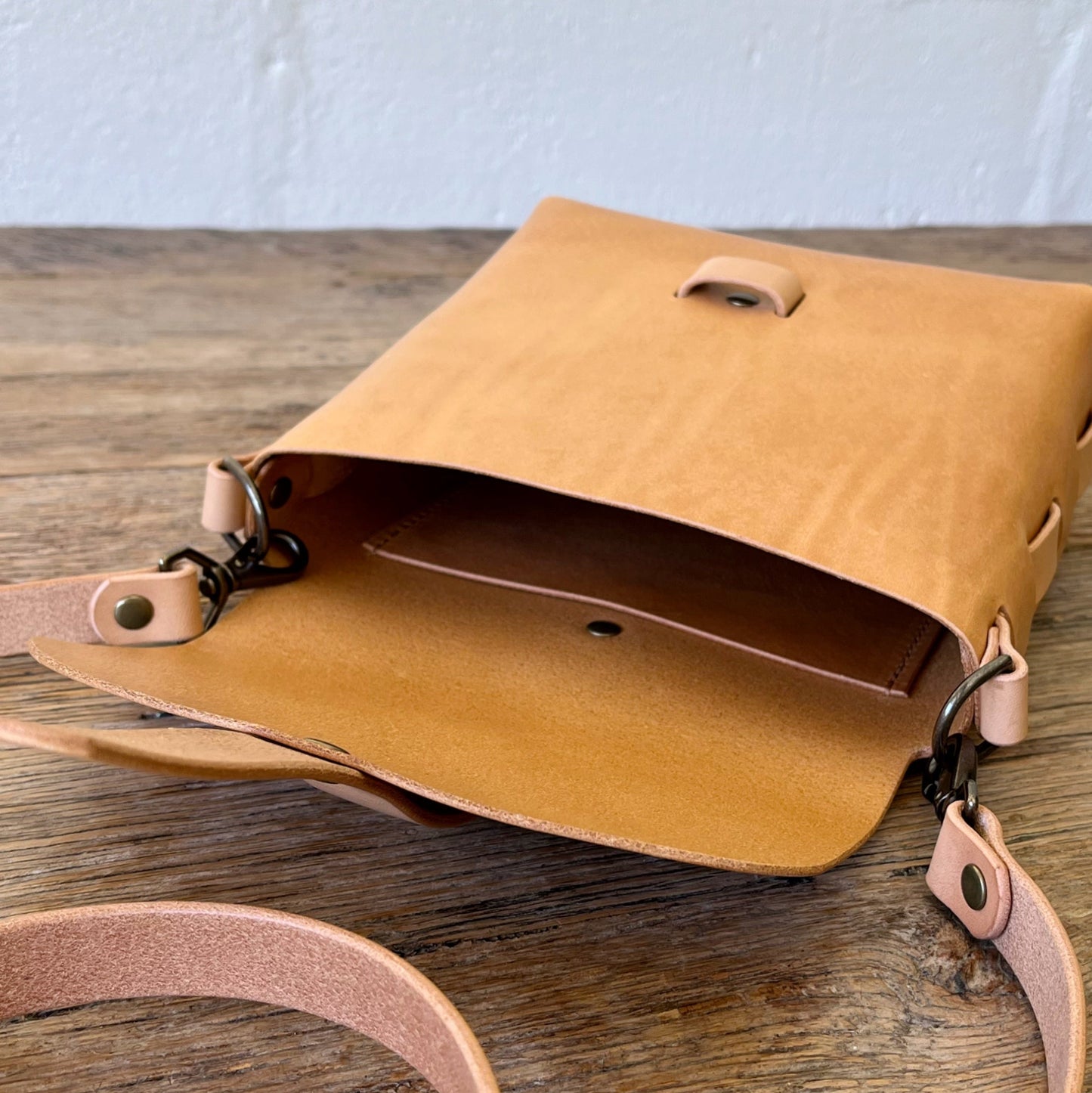 Tan leather bag with natural straps on a wooden surface