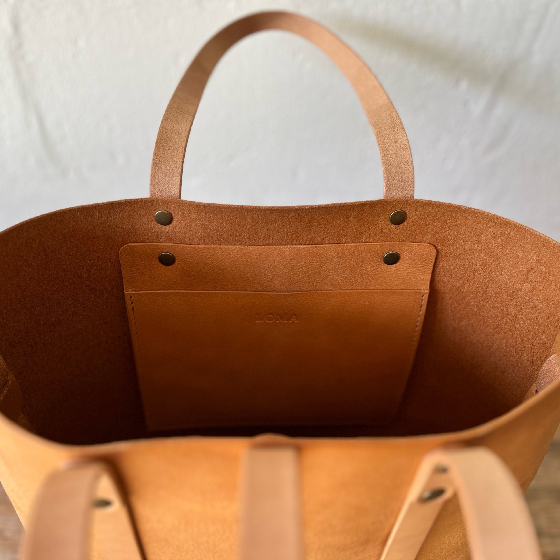 Brown leather tote bag with a visible brand name on a white background