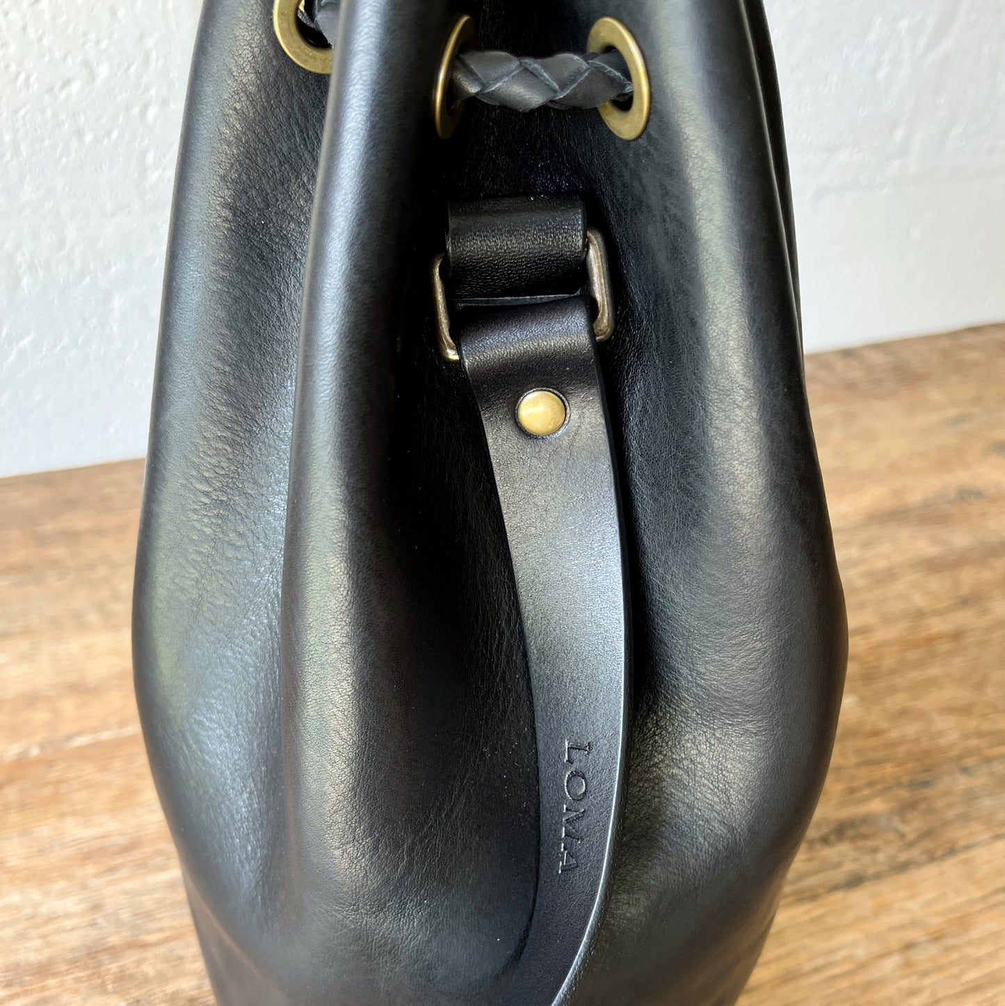 Black leather bag with gold hardware on a wooden surface