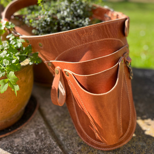 Brown leather tool pouch with plant pots in the background