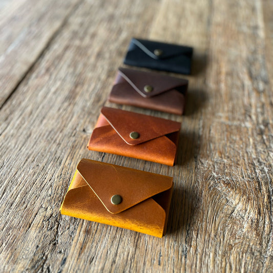 Set of four small leather wallets in different colors on a wooden surface