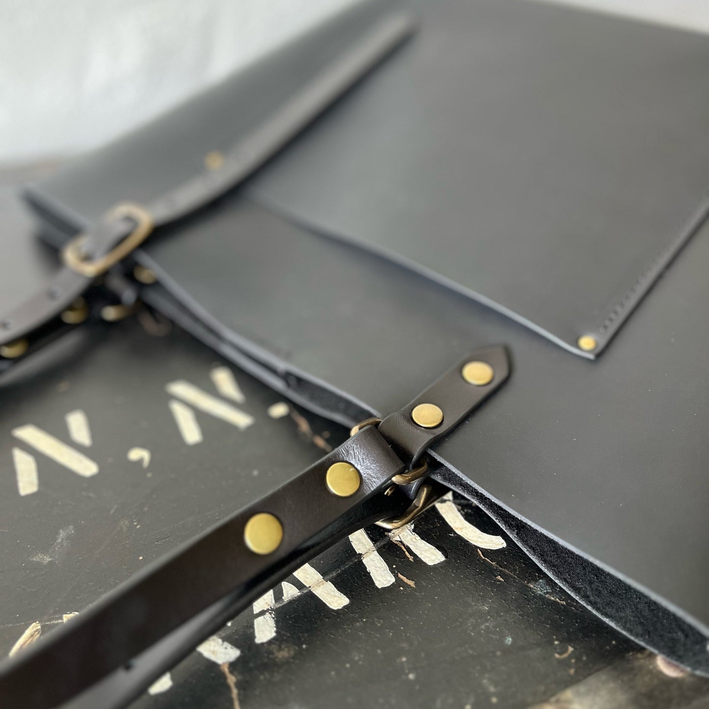 Black leather bag with brass studs on a white background