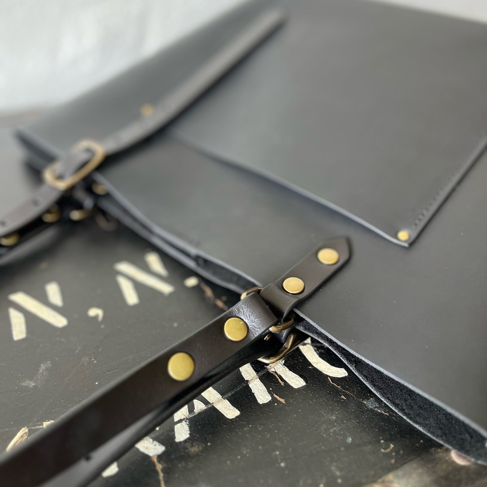 Black leather bag with brass studs on a white background