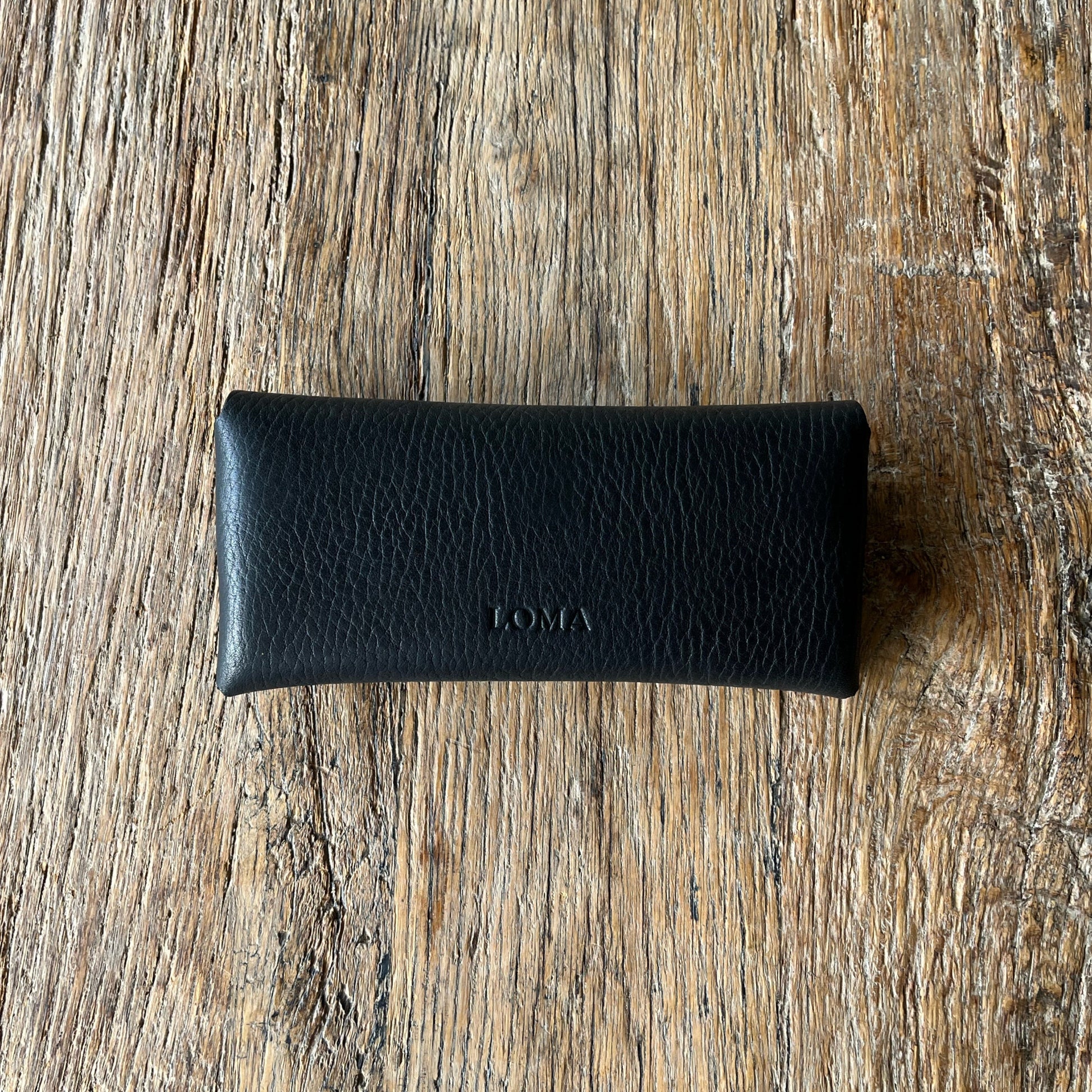 Black leather glasses case on a wooden surface