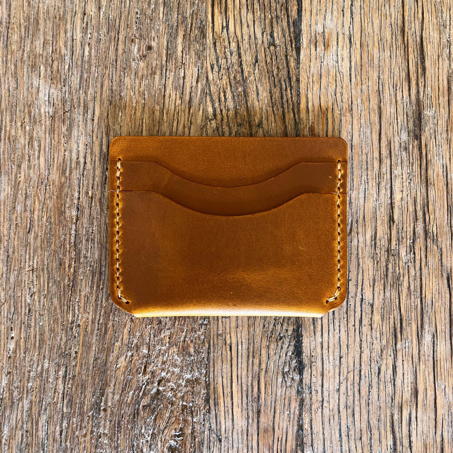Brown leather cardholder on a wooden surface