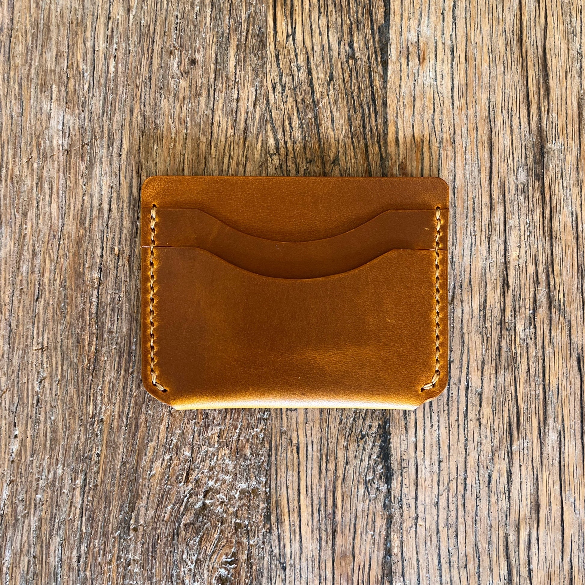 Brown leather cardholder on a wooden surface