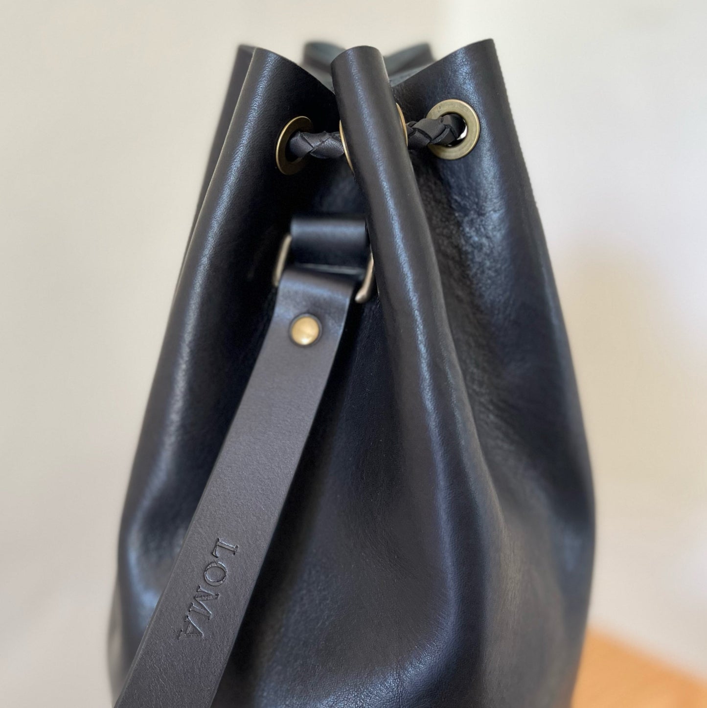 Close-up of a black leather handbag with visible branding on a light background