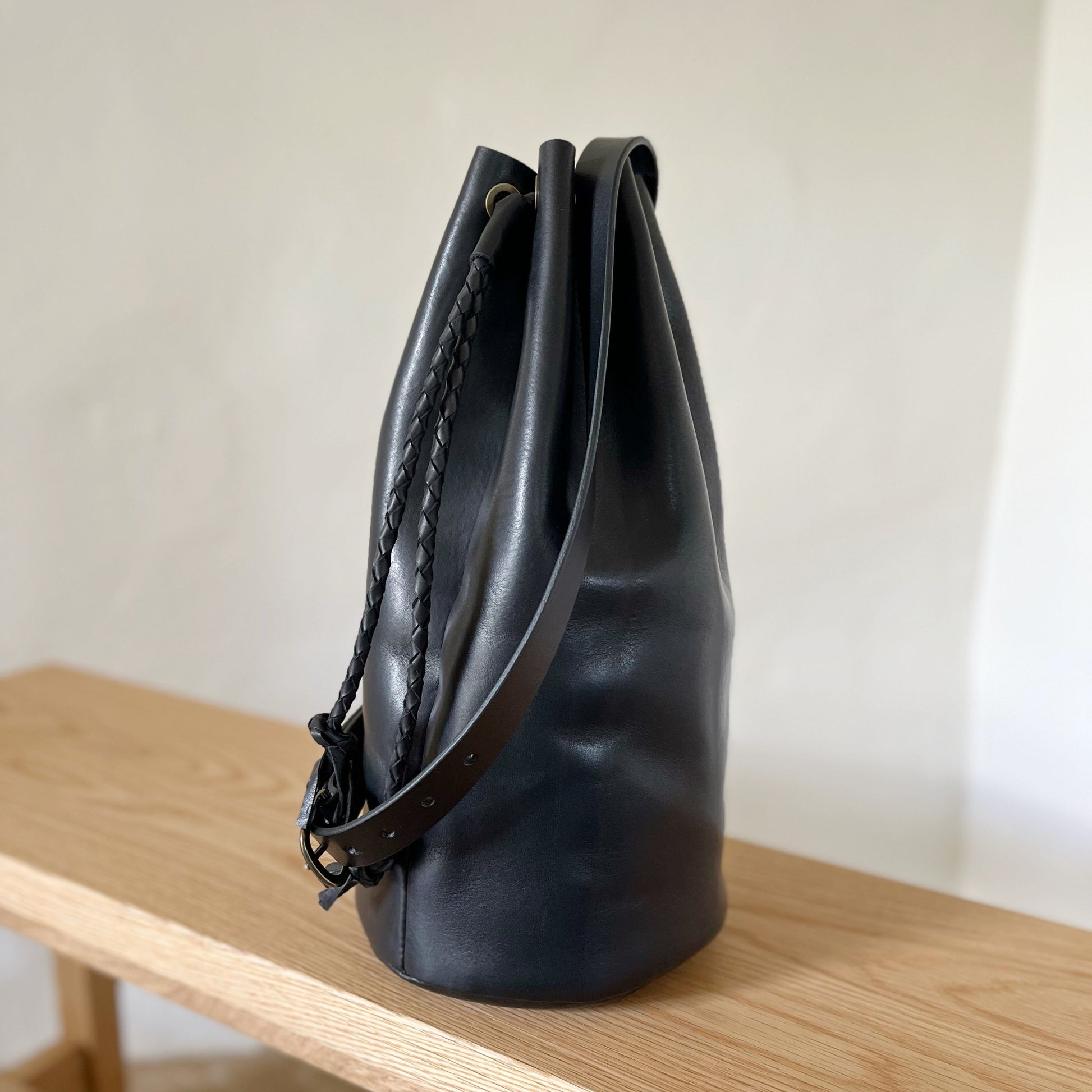 Black leather bag on a wooden surface with a neutral background